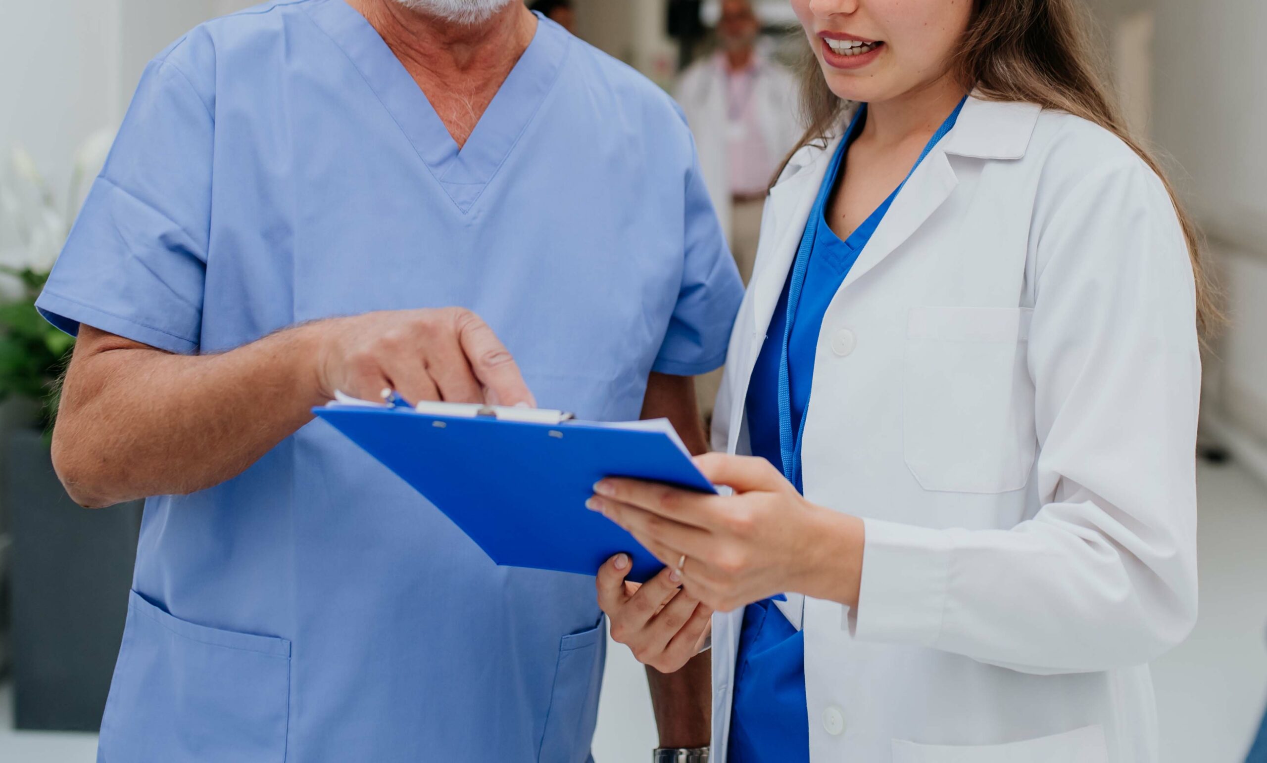 Two doctors speaking in the corridor pointing to a clipboard